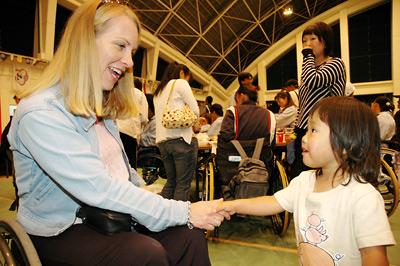 国際車いすテニス大会国際交歓会 で選手子供が握手している写真