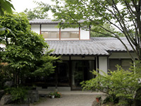 緑の木々に囲まれた日本家屋の写真